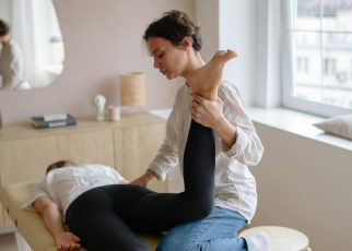 Physiotherapist aiding a woman with leg exercises on a massage table for relaxation and therapy.